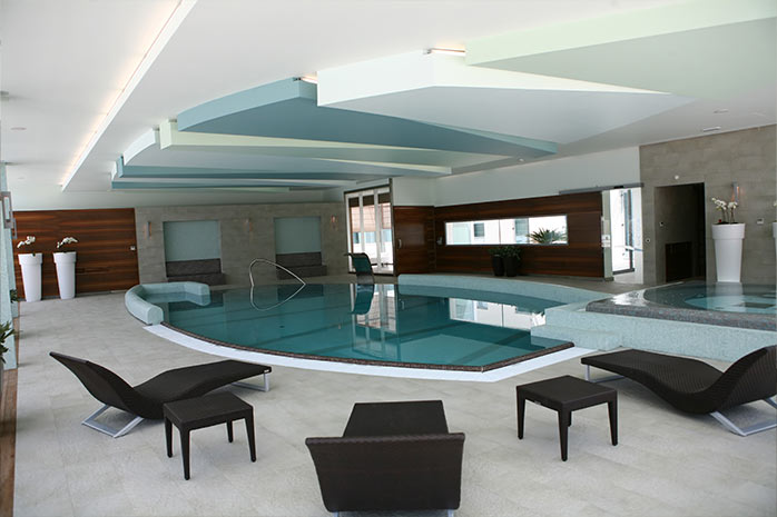 "Wellnessbereich im Hotel mit Schwimmbad, umgeben von Liegestühlen"